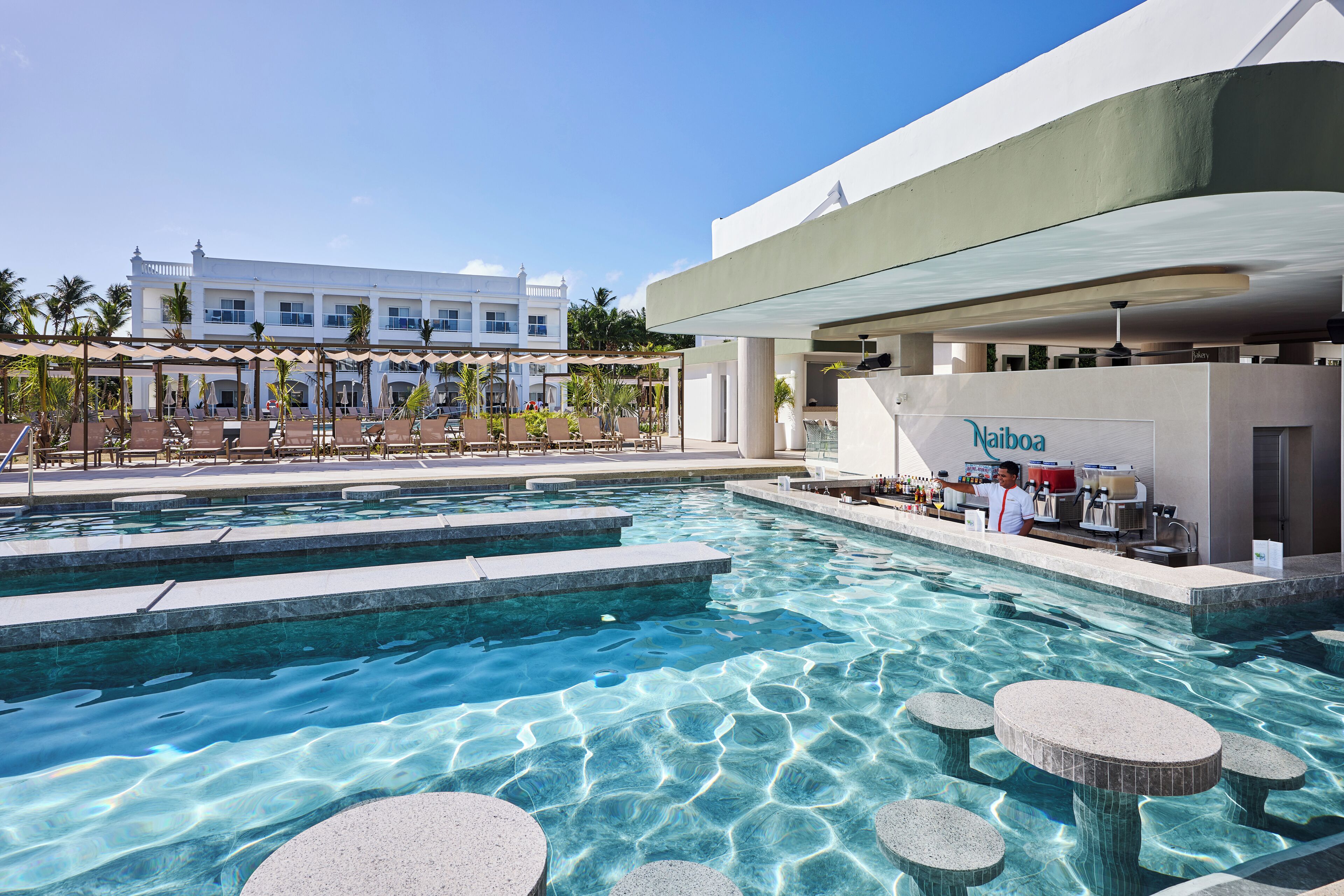 A pool area with clear water, lounge chairs, and a bar area.