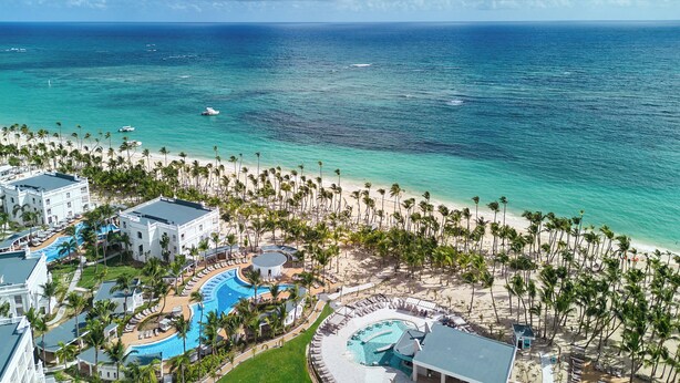 A resort with multiple swimming pools, a beach, and a view of the ocean.