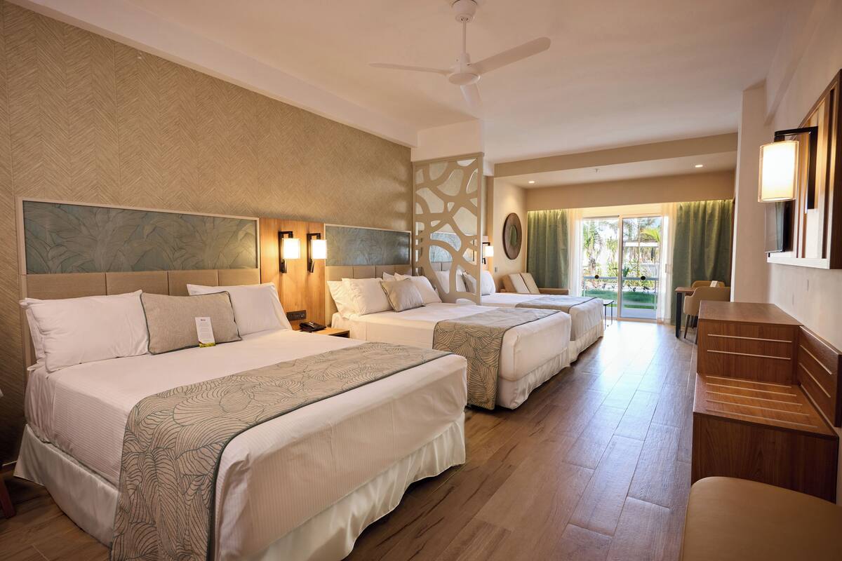 Une chambre d’hôtel avec deux lits, un plancher en bois, un ventilateur de plafond et une vue sur l’extérieur.