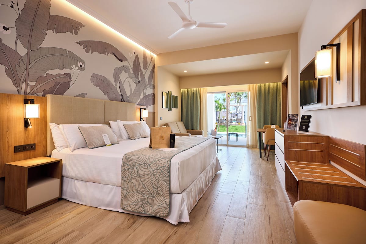 Une chambre d’hôtel avec un grand lit, des tables de chevet, un bureau et une télévision.