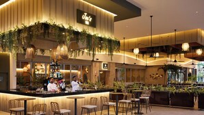 A modern bar area with a neon sign, wooden bar counter, and several seating options.