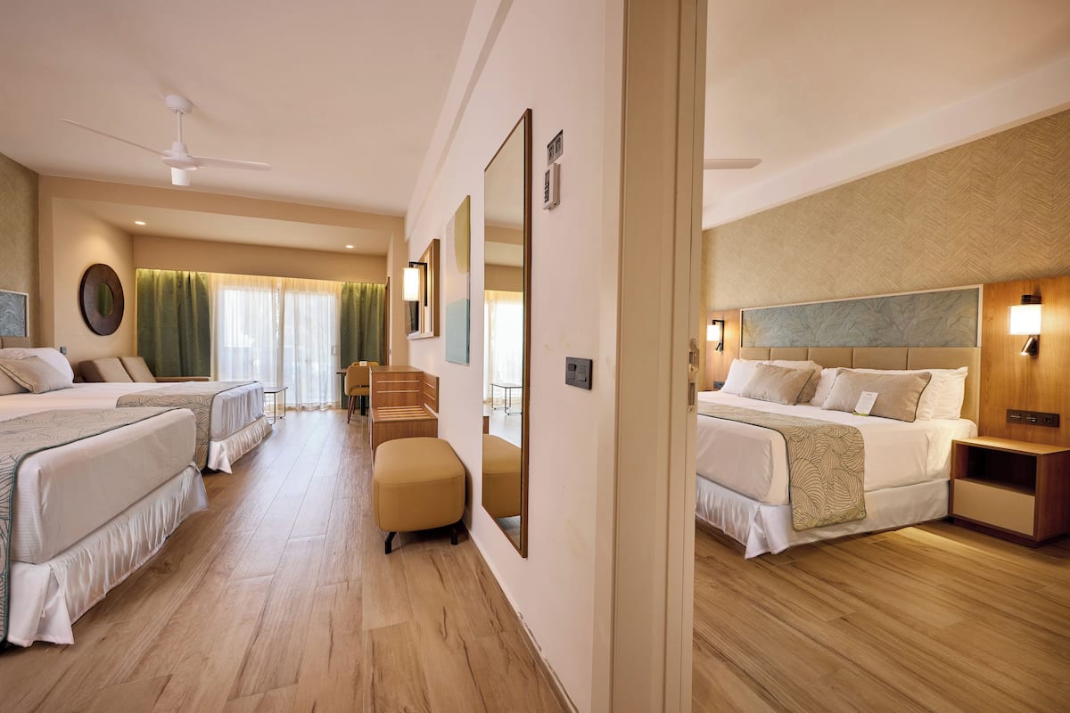 Une chambre d’hôtel avec deux lits, un coin salon et un grand miroir.