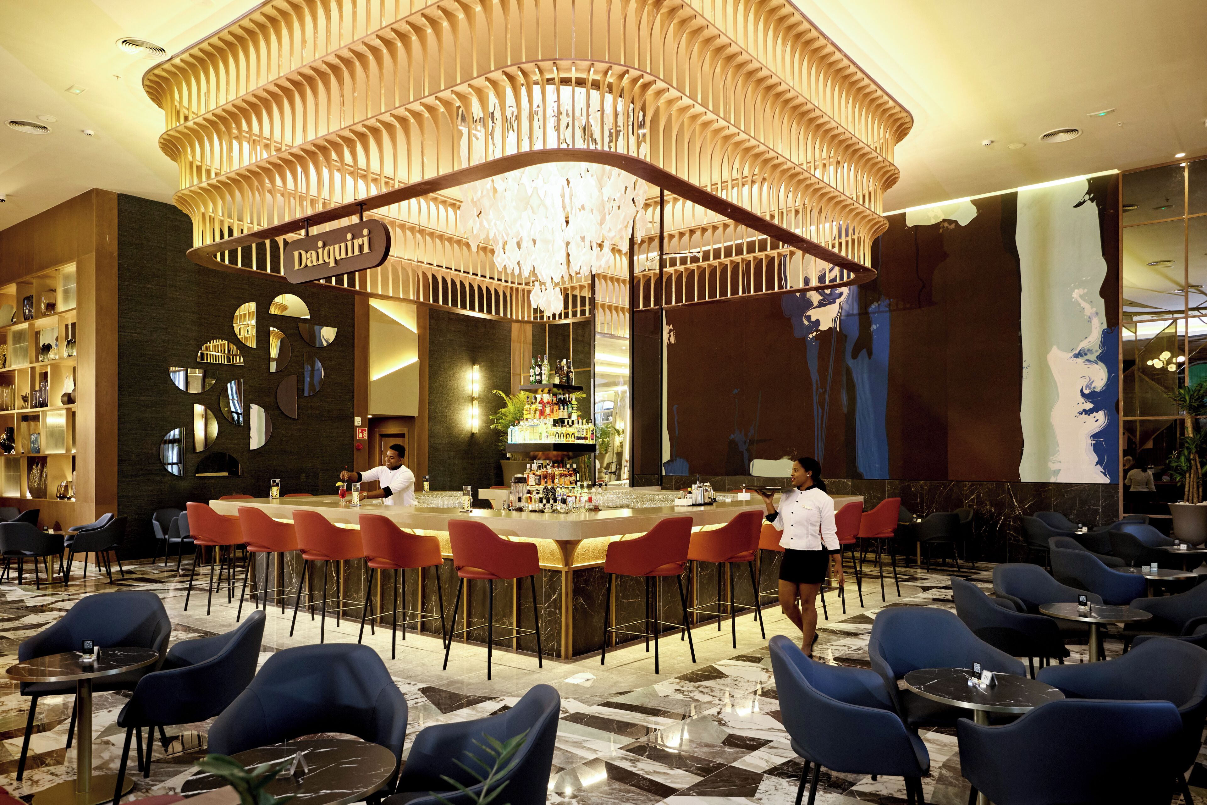 Un espace bar au design moderne, comprenant une structure de plafond originale et un comptoir avec des tabourets.