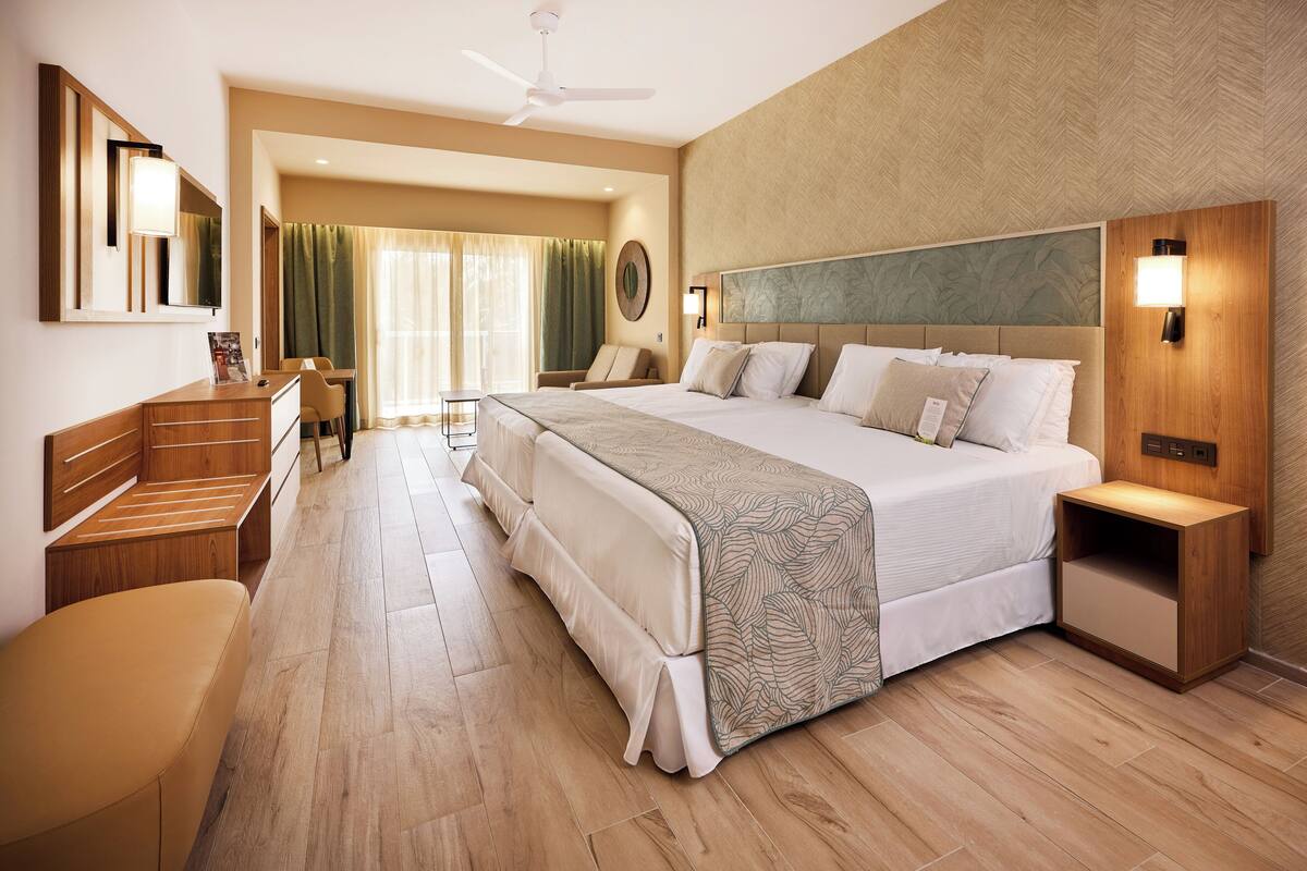Une chambre d’hôtel avec un grand lit, un bureau, une chaise, une coiffeuse et un miroir.