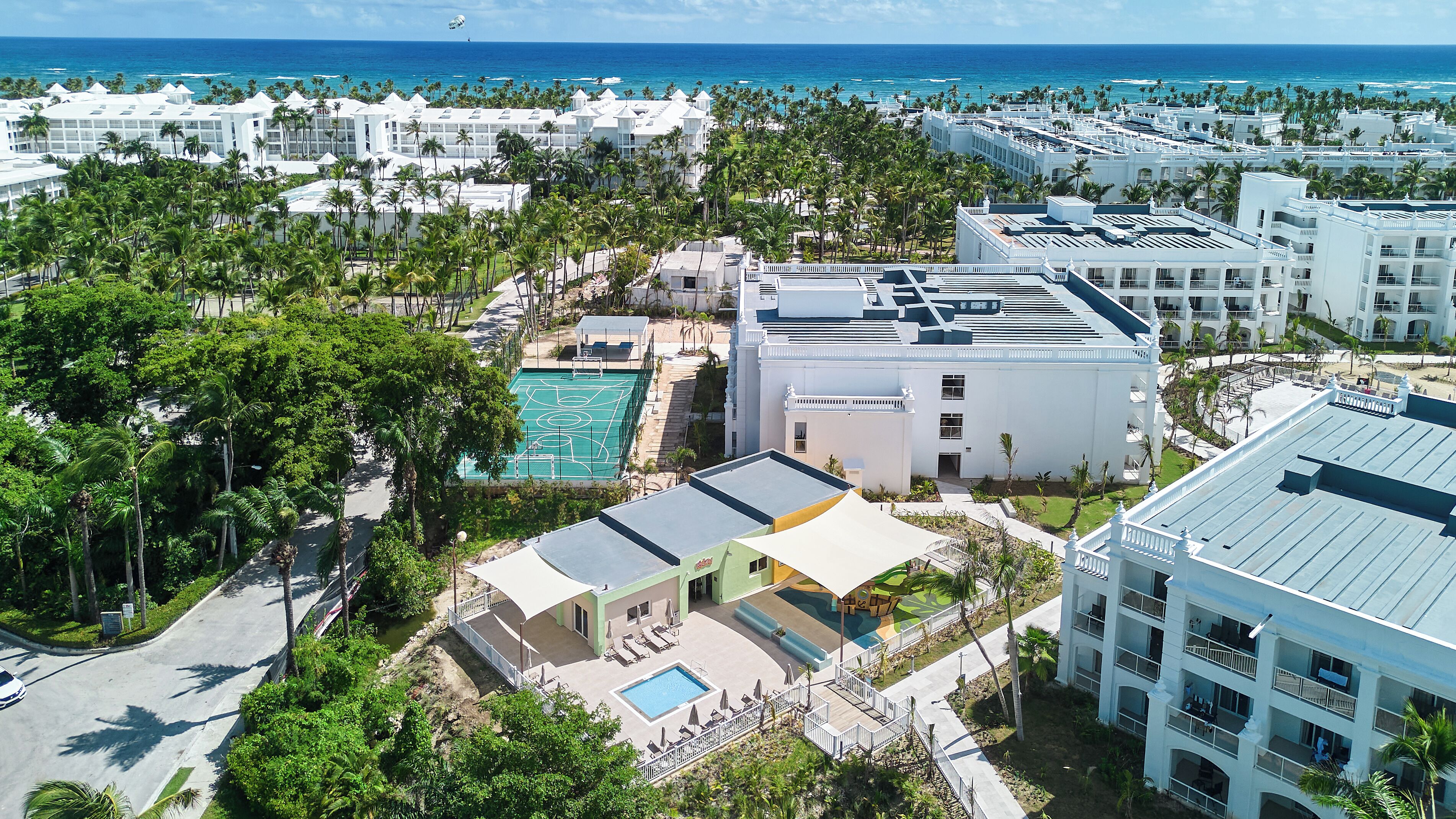 Un resort con varias edificaciones, una piscina y una cancha de tenis.