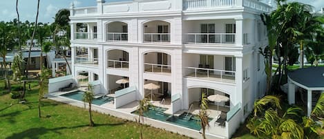 A multi-story hotel with a pool, outdoor seating, and palm trees.