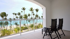 A balcony with a view of the beach and palm trees.
