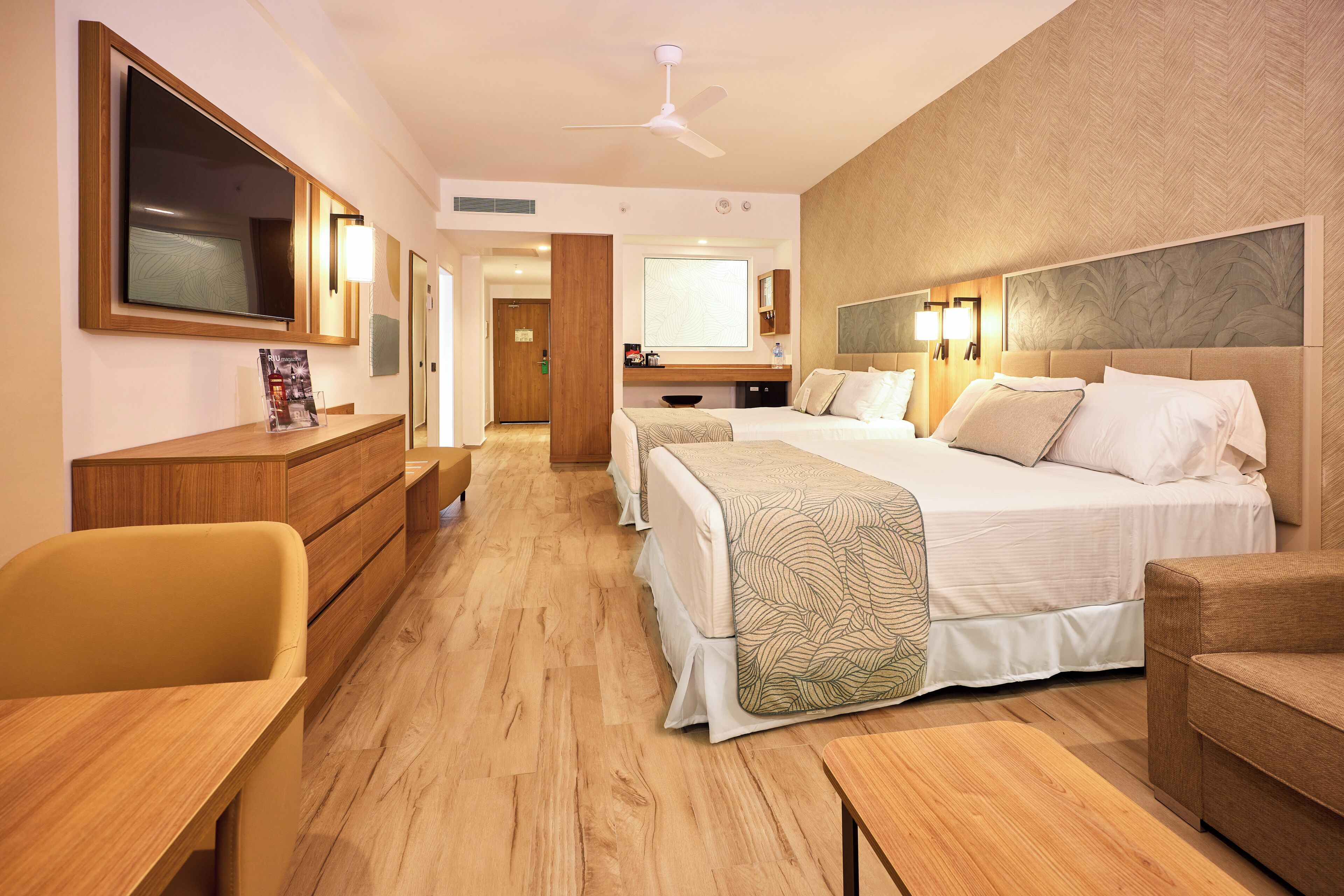 A hotel room with a large bed, a desk, a chair, and a television.
