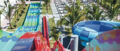 Un tobogán de agua con múltiples carriles, rodeado de palmeras y una zona de piscina.