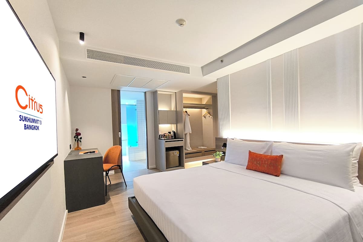 A modern hotel room with a large bed, a desk, and a seating area.