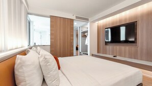A modern hotel room with a large bed, a flat-screen TV mounted on the wall, and a walk-in closet. - Citrus Sukhumvit 13 Nana Bangkok by Compass Hospitality (Bangkok)