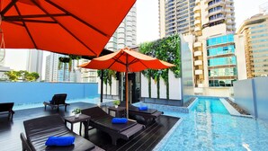 A rooftop pool area with lounge chairs, an umbrella, and a view of surrounding high-rise buildings. - Citrus Sukhumvit 13 Nana Bangkok by Compass Hospitality (Bangkok)