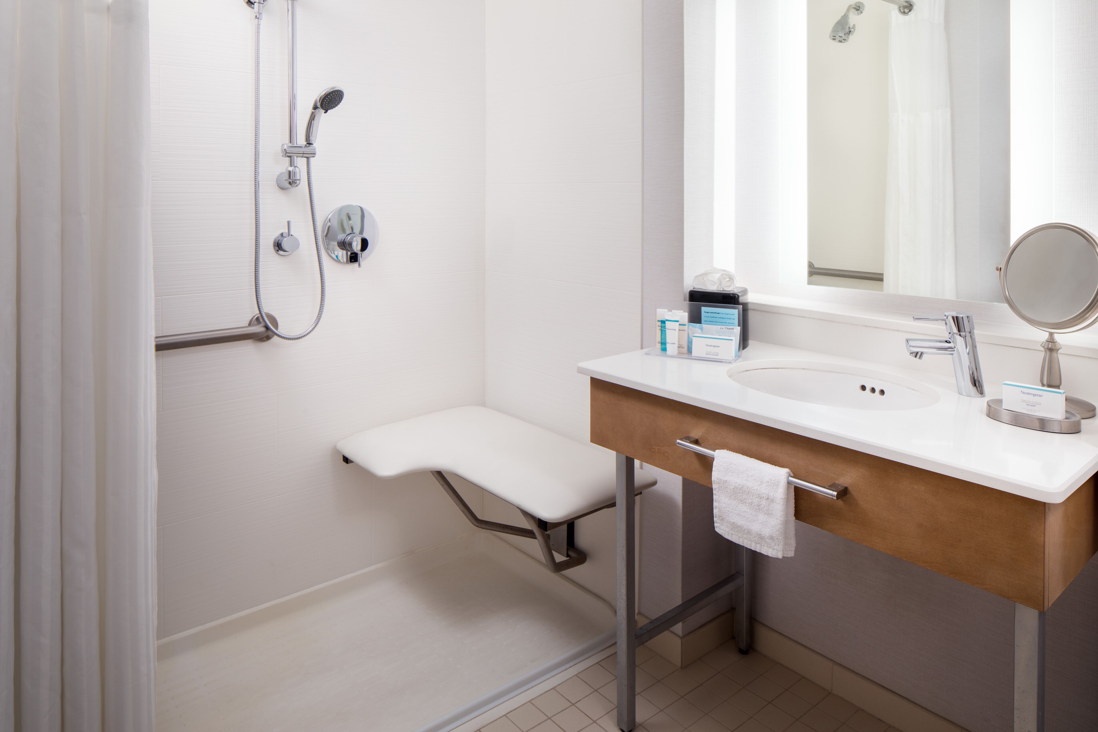 A modern bathroom with a shower, a sink with a towel, and a mirror.