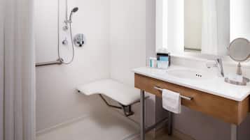 Een moderne badkamer met een douche, een wastafel met een handdoek en een spiegel.