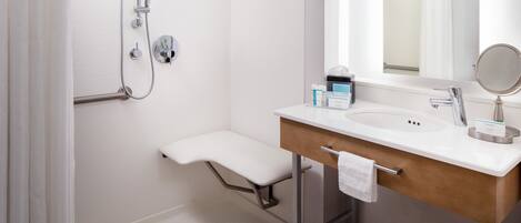 Une salle de bain moderne avec une douche, un lavabo avec une serviette et un miroir.