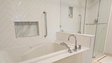 A modern bathroom with a large bathtub, a glass-enclosed shower, and a herringbone-patterned wall.