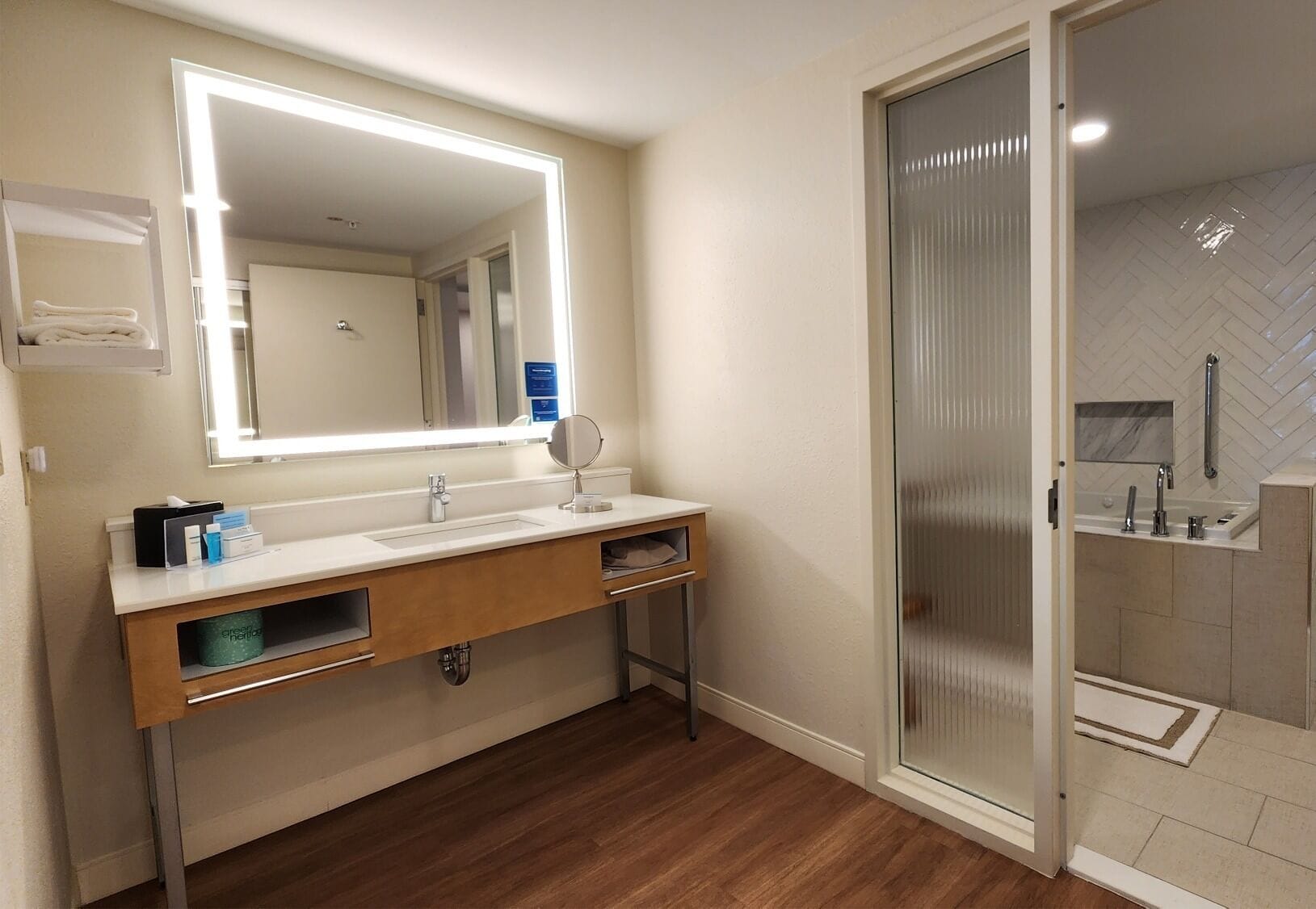 A modern bathroom with a large mirror, two sinks, and a shower area.