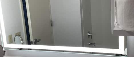 Un baño con un espejo grande, un lavabo y un perchero para toallas.