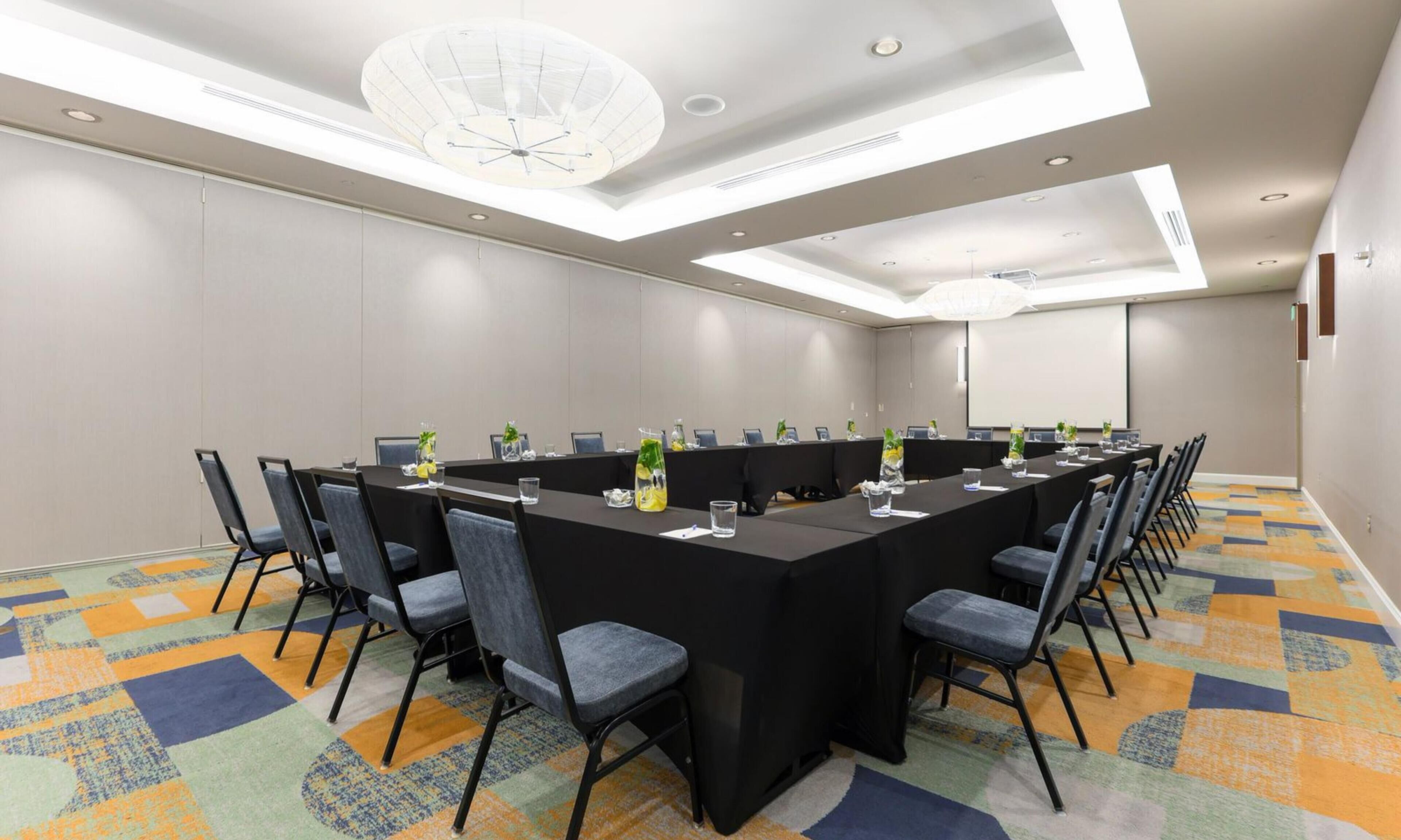 A conference room with a long table, chairs, and a patterned carpet.