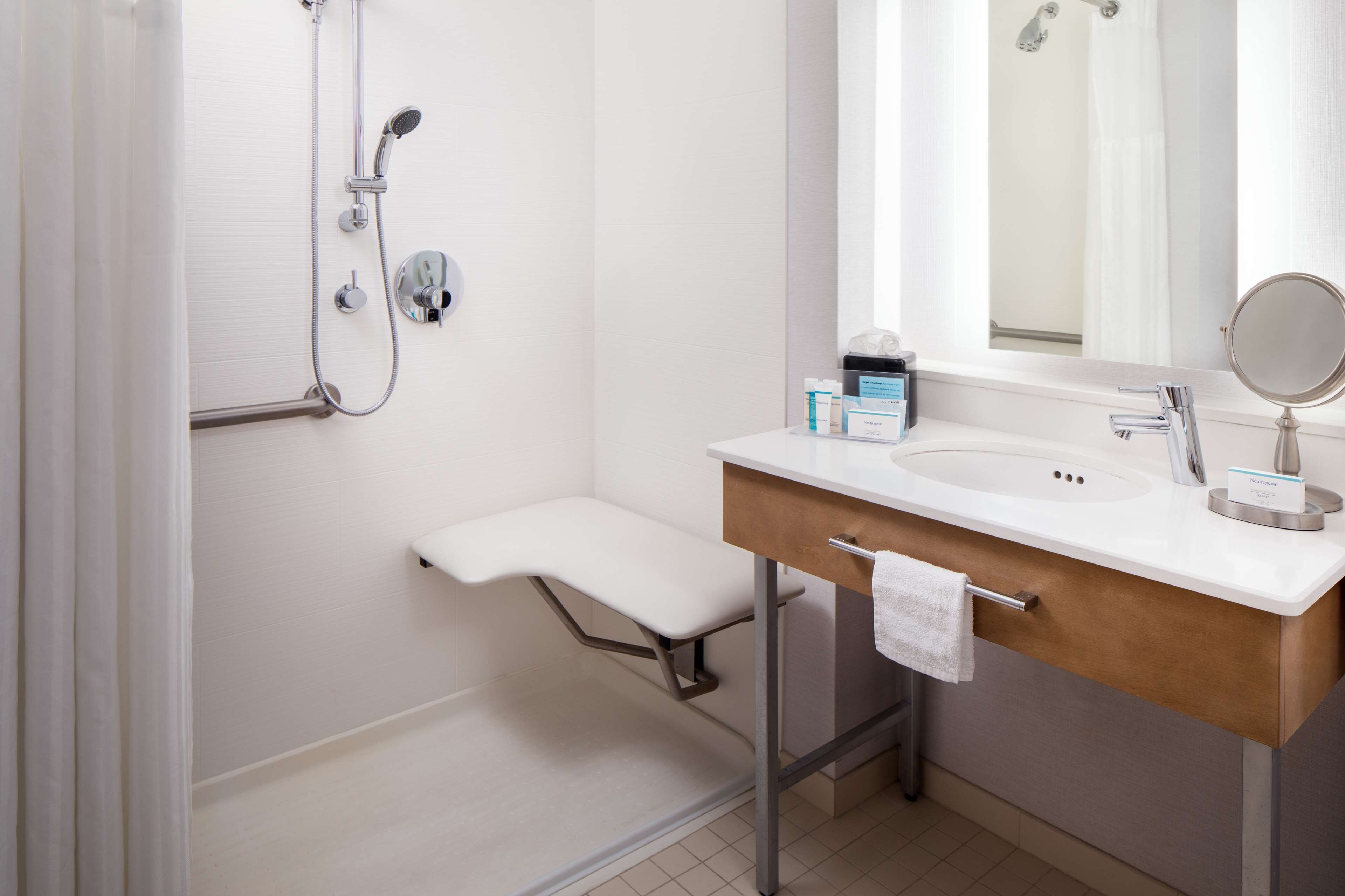 A modern bathroom with a shower, a sink with a mirror, and a towel rack.