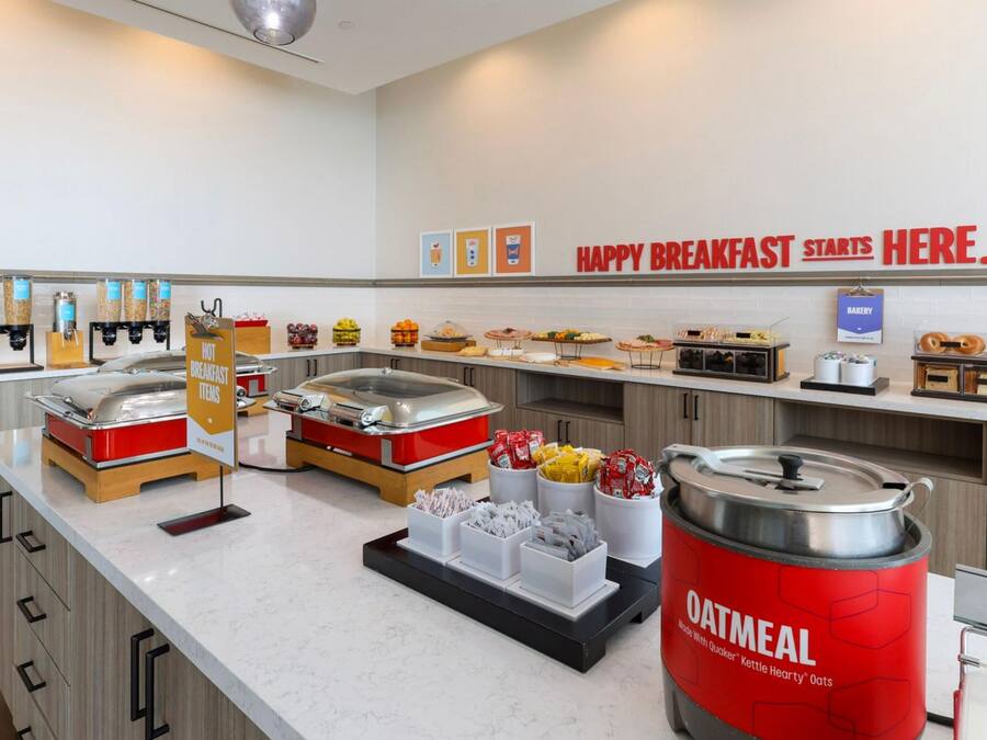 Ein Frühstücksbuffet mit verschiedenen Speisen und einem Schild mit der Aufschrift 'HAPPY BREAKFAST STARTS HERE'.