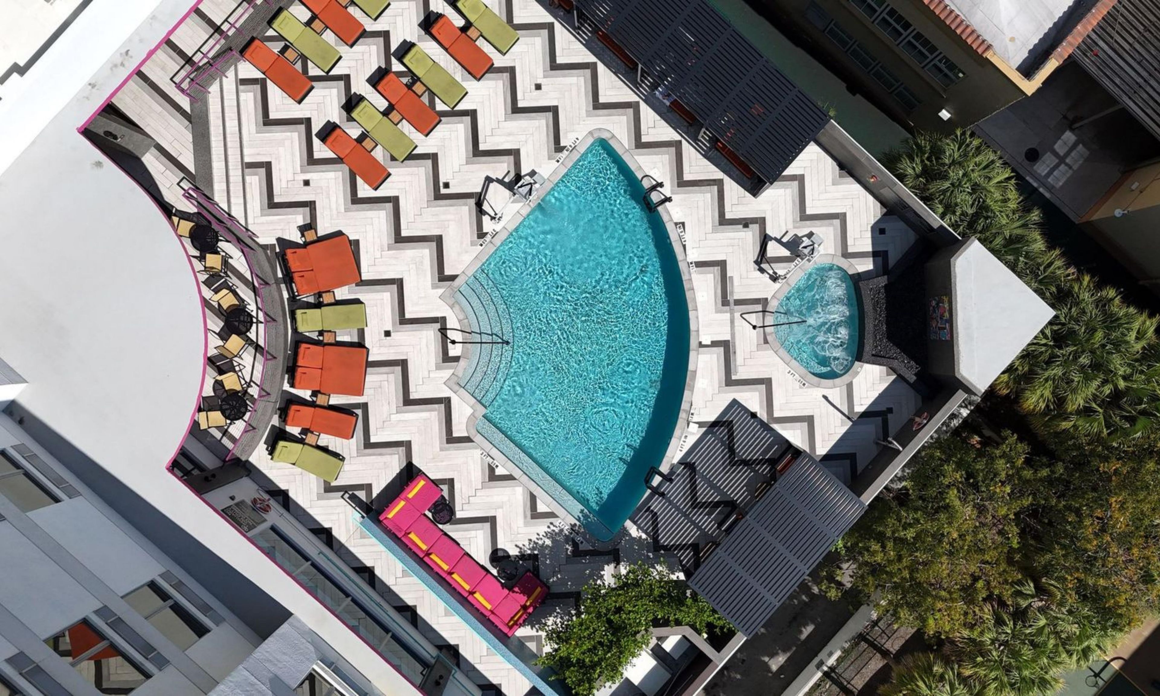 Ein Dachpool mit einem Zickzack-Fußboden, umgeben von Sitzgelegenheiten im Freien und einem kleinen Brunnen.