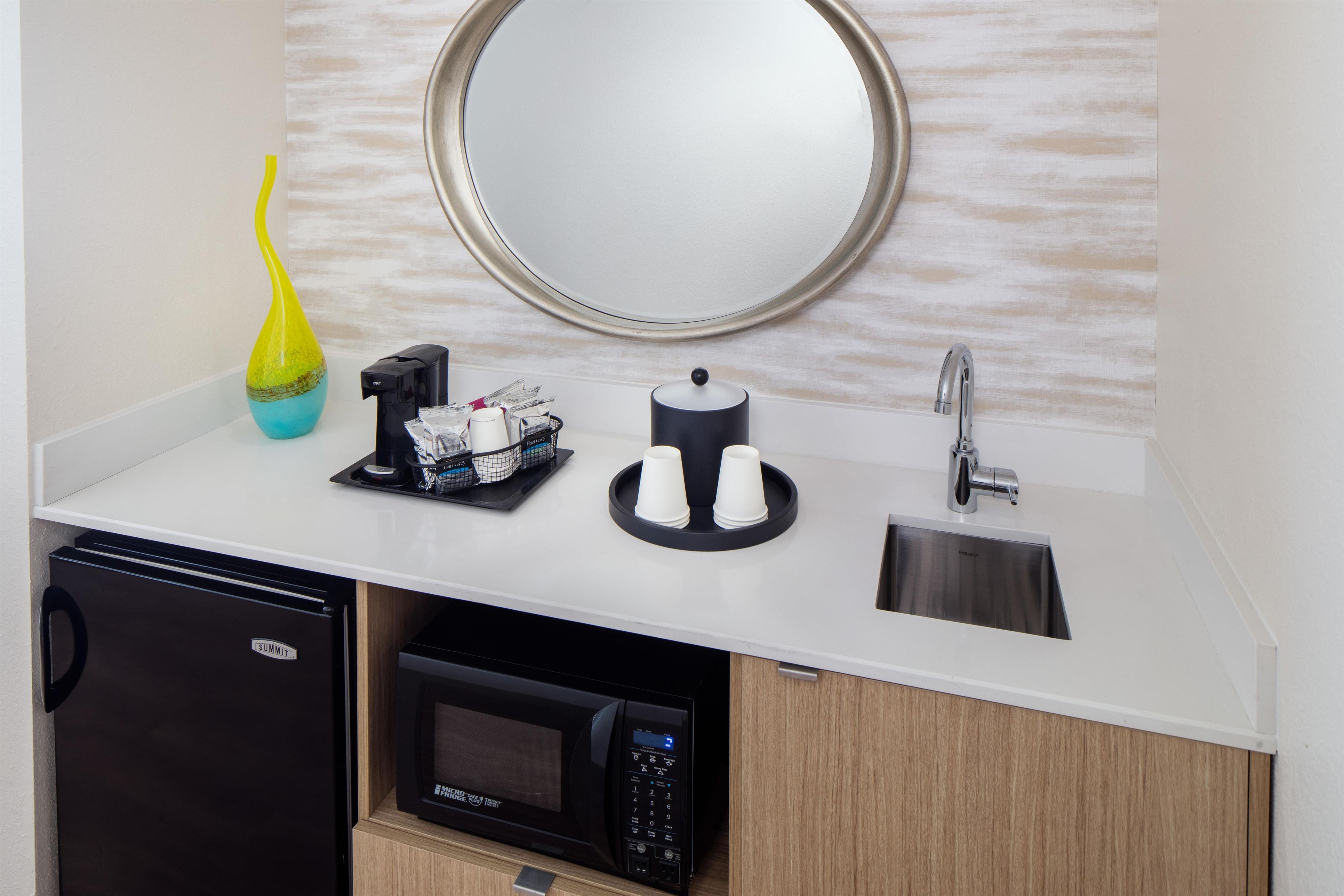A modern kitchen with a built-in dishwasher, a microwave, a coffee machine, and a sink with a faucet.