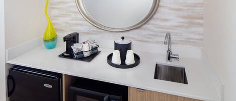 A modern kitchen with a built-in dishwasher, a microwave, a coffee machine, and a sink with a faucet.