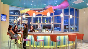 Een bar met een gebogen toonbank, verschillende krukken en een barman.