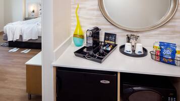Una habitación de hotel con kitchenette, cafetera, microondas y refrigerador pequeño.