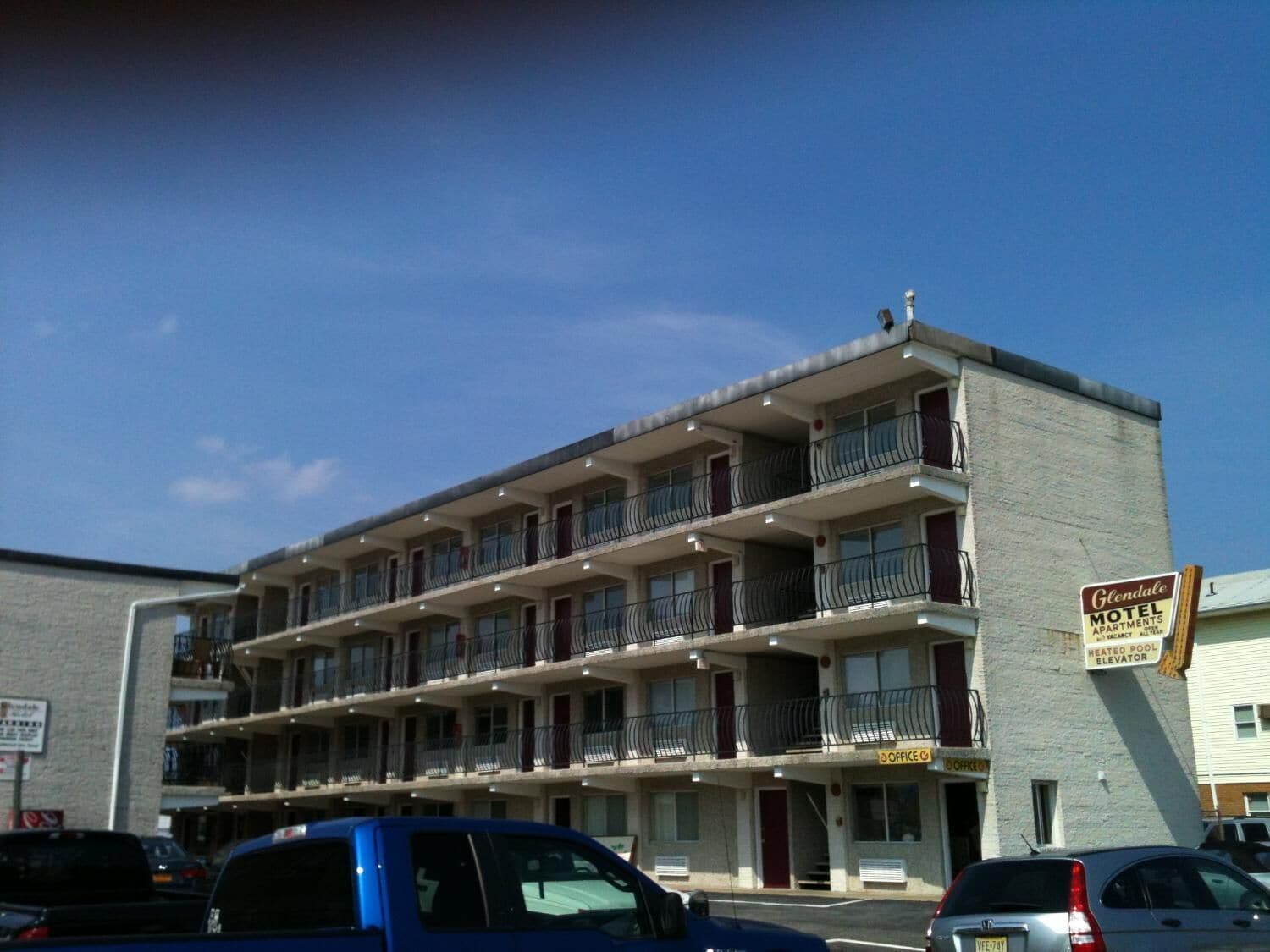 Ein Motel mit mehreren Etagen, jede mit Balkonen, und einem Schild, das einen beheizten Pool und einen Aufzug anzeigt.