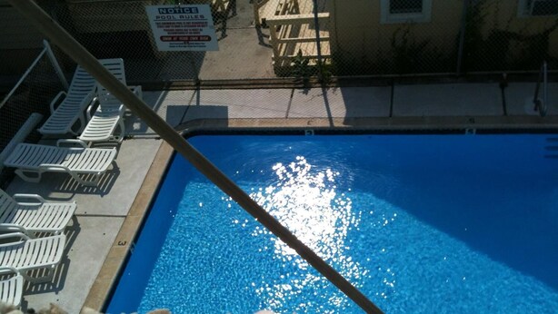 A swimming pool with lounge chairs and a notice sign. - Glendale Motel (Seaside Heights)