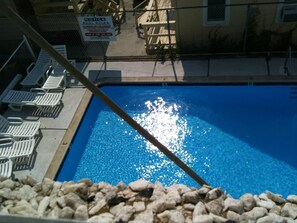 A swimming pool with lounge chairs and a notice sign. - Glendale Motel (Seaside Heights)