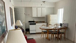A compact living space with a dining area, kitchenette, and a red sofa. - Glendale Motel (Seaside Heights)