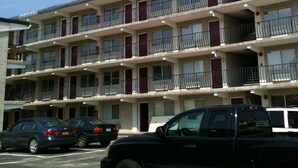 A multi-story motel with balconies, a parking lot, and several parked cars. - Glendale Motel (Seaside Heights)