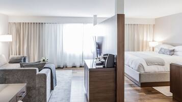 A modern hotel room with a sofa, desk, and bed.