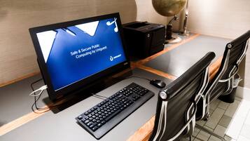 A desk with a computer monitor displaying a message about secure public computing, a keyboard, a mouse, a printer, and a globe on a stand.