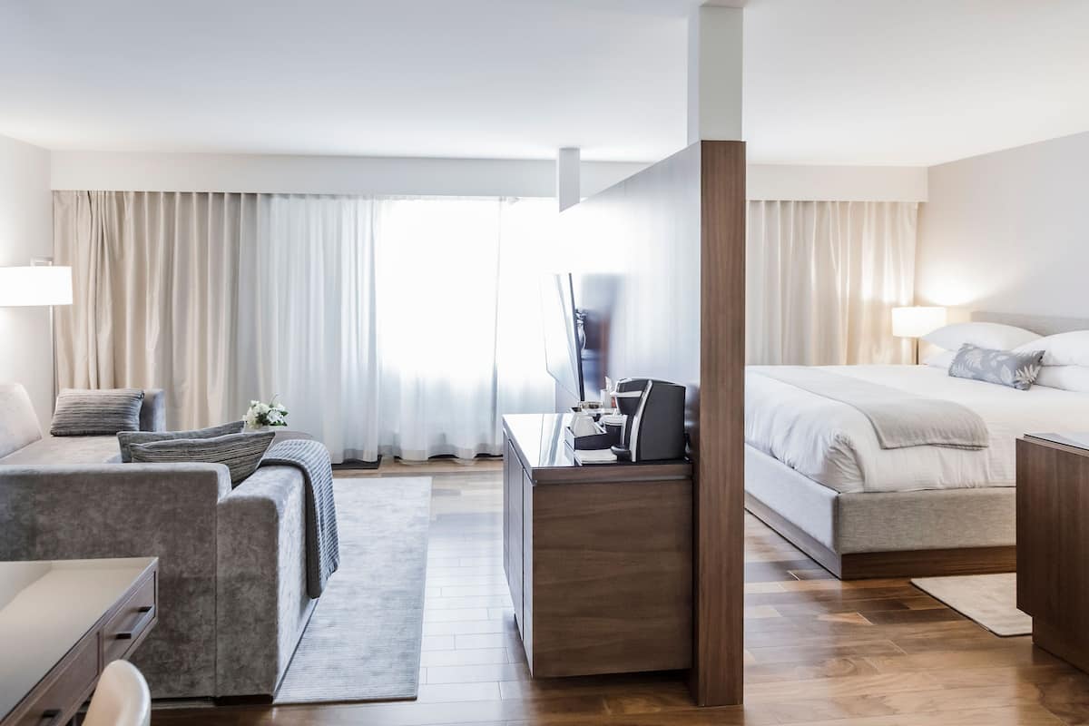 A modern hotel room with a bed, desk, and seating area.