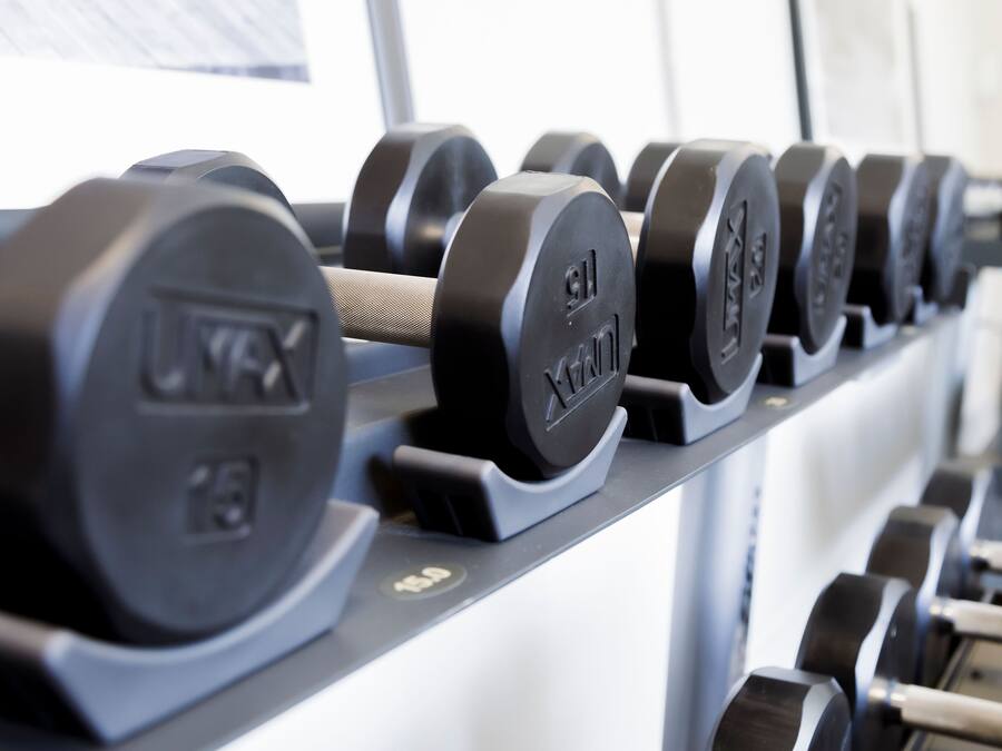 Estante con mancuernas y marcas de peso, que indica un gimnasio.