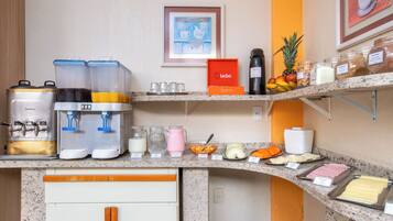 Una barra de desayuno con máquinas de café, dispensadores de leche y una variedad de alimentos.