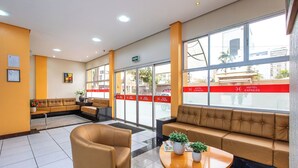 Un hall de hotel con zonas de estar, mostrador de recepción y ventanas amplias.