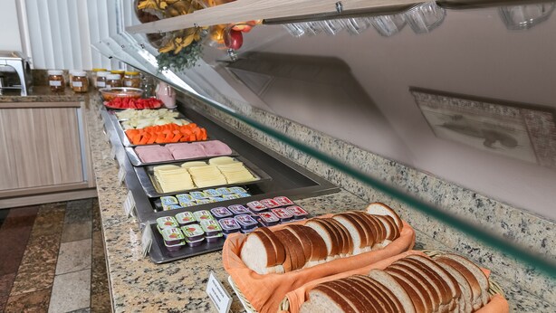 Un buffet proposant une variété d’aliments, notamment du pain tranché, des fruits et des condiments.