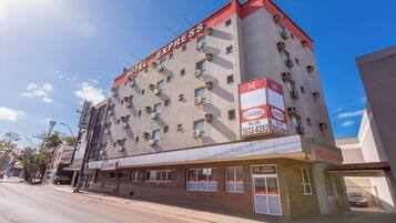 Un hotel de varios pisos con letrero 'HOTEL EXPRESS', unidades de aire acondicionado y una entrada visible.