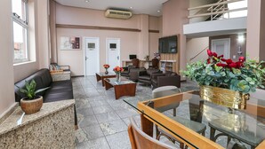 Un vestíbulo de hotel con mostrador de recepción, zona de estar y una escalera.
