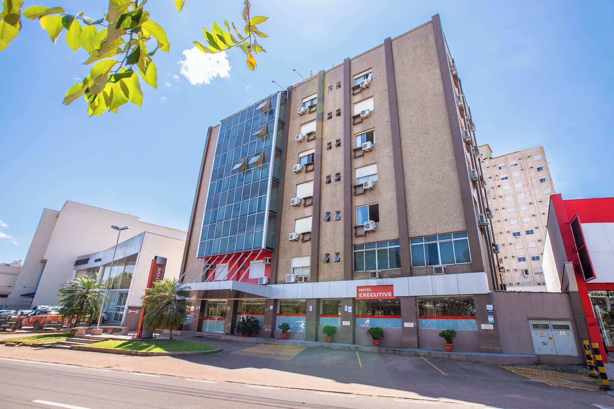 Un hôtel à plusieurs étages doté d’une façade moderne en verre, d’une entrée bien visible et d’une enseigne indiquant « Hôtel Executive ».