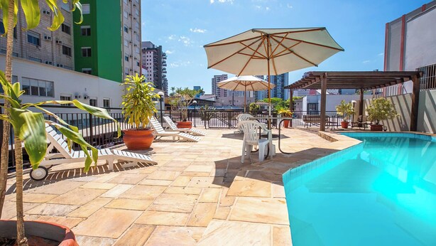 A rooftop pool area with lounge chairs, umbrellas, and potted plants. - Hotel Suárez Executive Novo Hamburgo (Novo Hamburgo)