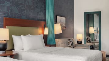 Ein Hotelzimmer mit einem großen Bett, zwei Nachttischen mit Lampen, einer Sitzecke mit einem Sessel, einem Spiegel und einer Wand mit geometrischem Muster.