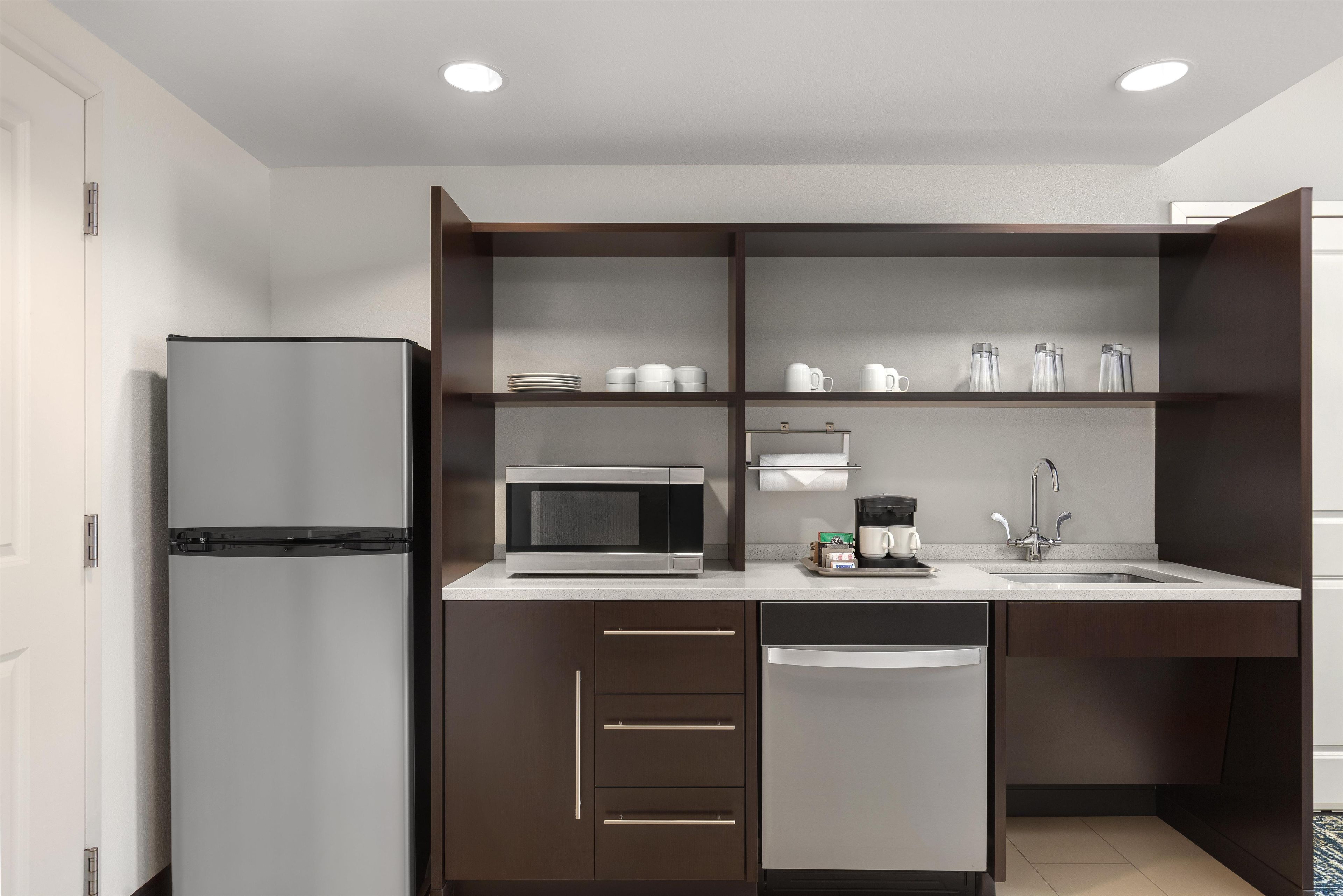 Eine moderne Küche mit einem integrierten Kühlschrank, einer Mikrowelle und einer Kaffeemaschine.