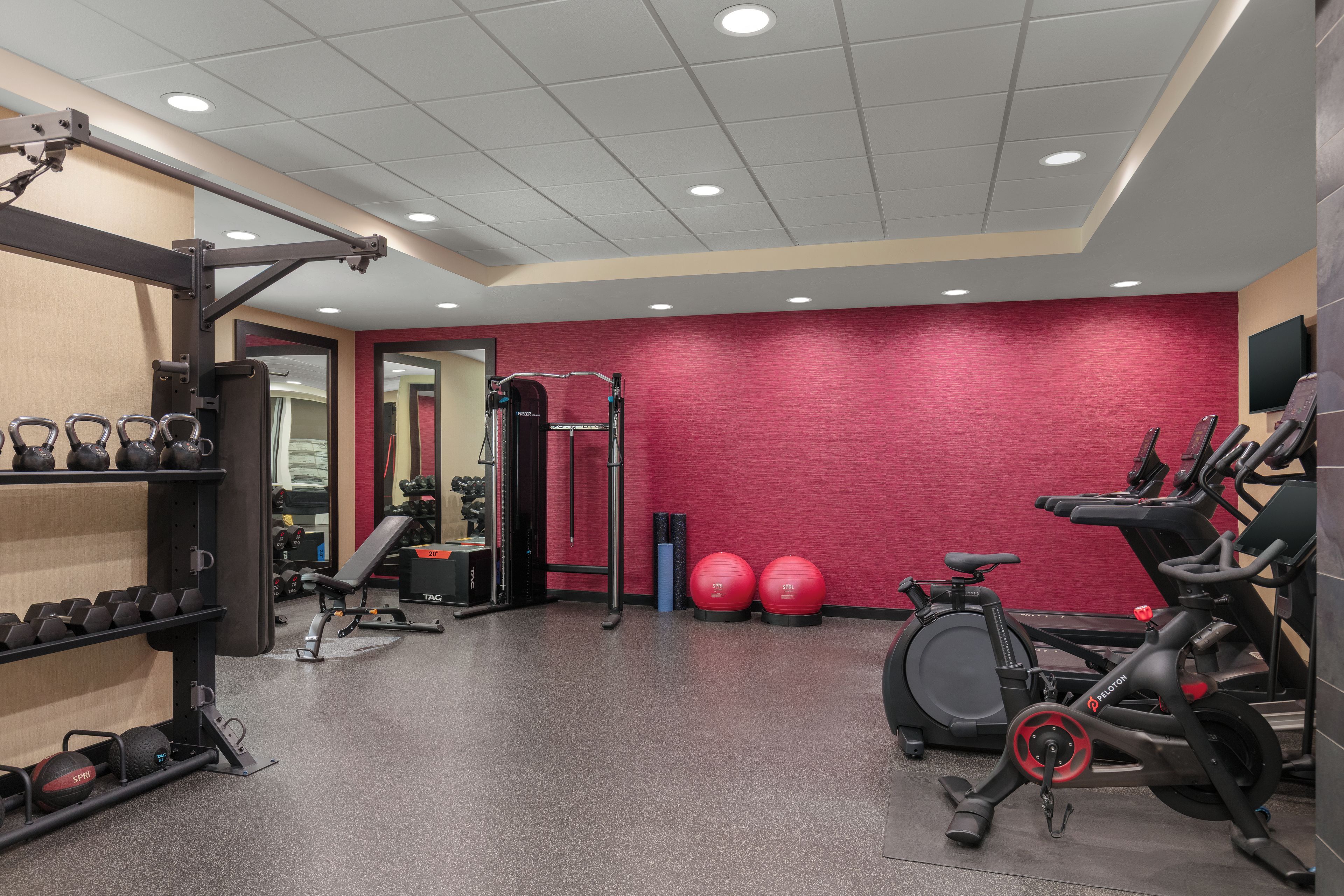 A gym with exercise equipment, a bench, kettlebells, and a treadmill.
