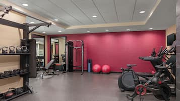 A gym with exercise equipment, a bench, kettlebells, and a treadmill.